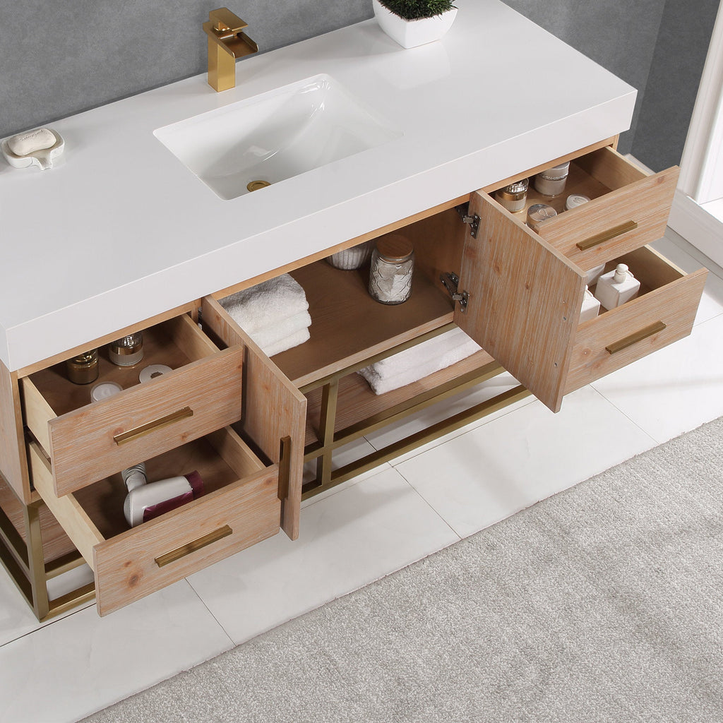 Overhead view of a modern 60-inch single-sink bathroom vanity with a white composite stone top and rectangular undermount sink, light natural wood cabinet on a gold metal base, brass faucet and handles, open drawers with towels and toiletries.