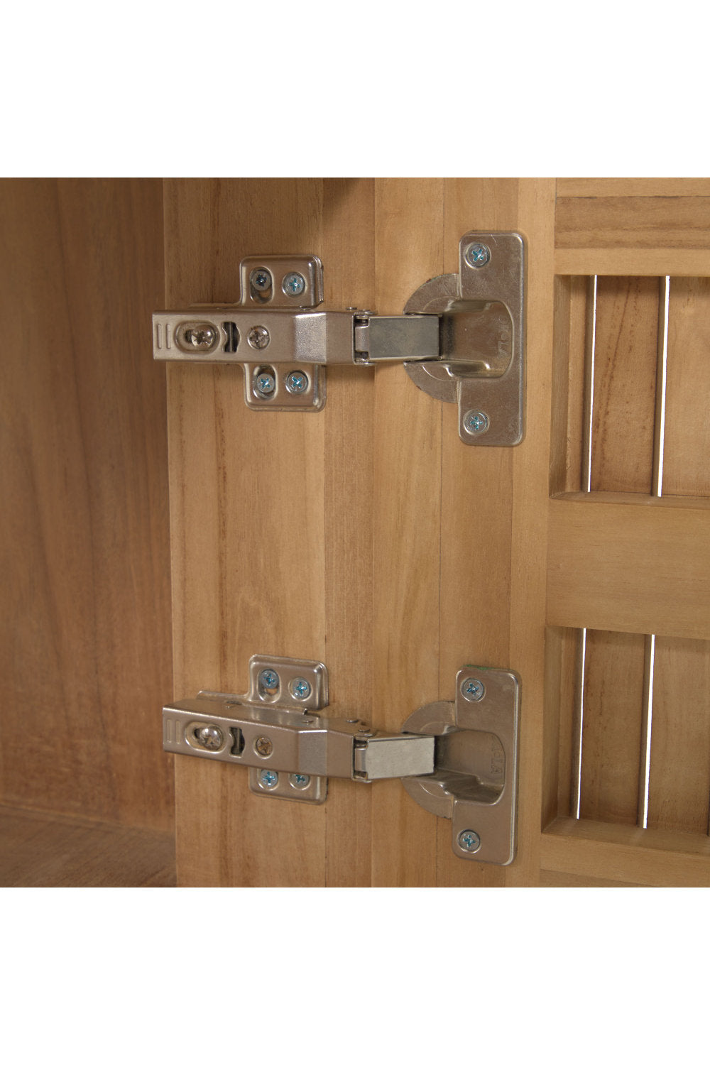 Close-up of two metal concealed cabinet hinges mounted to the natural solid wood interior and slatted vanity door, showing screw plates and hinge arms on a modern bathroom vanity.