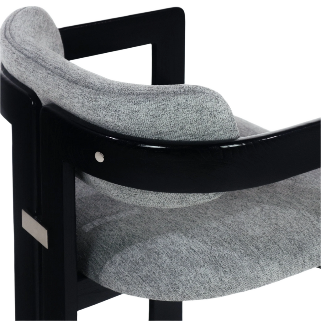 Close-up of a modern dining chair showing grey boucle upholstery on the seat and curved backrest, a black stained wooden arm frame, and stainless metal accent hardware.