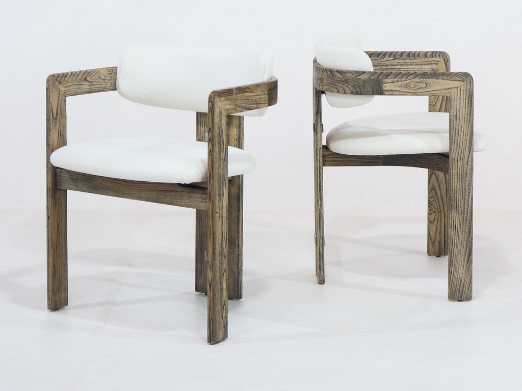 Two rustic brown natural wood dining chairs with white boucle upholstered seats and curved padded backrests, open-arm design and angled legs shown on a plain studio background.