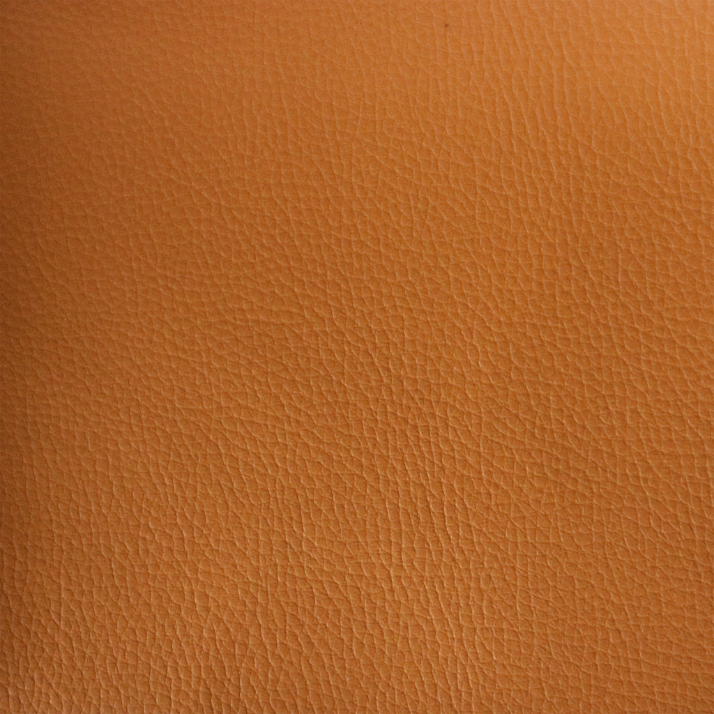 Close-up of tan leather upholstery showing fine pebble-grain texture and subtle natural creases, warm brown-tan color used for mid-century modern dining chair seats.