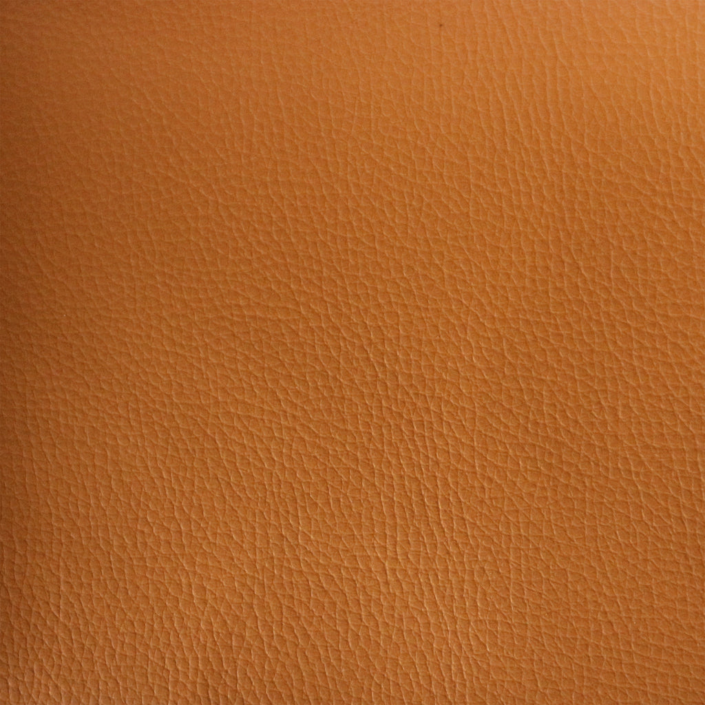 Close-up of tan leather upholstery showing fine pebble-grain texture and subtle natural creases, warm brown-tan color used for mid-century modern dining chair seats.
