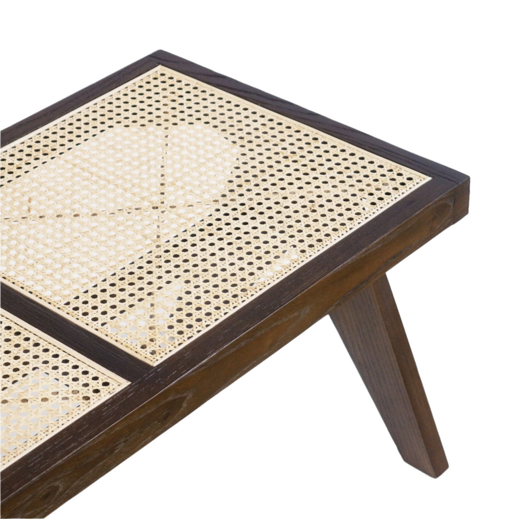 Close-up of a bench corner showing a natural cane-woven seat panel set in a warm natural wood frame with a dark-stained tapered leg, highlighting the modern mid-century inspired construction and woven cane texture.