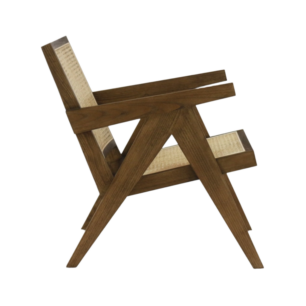 Side view of a low midcentury lounge chair with natural wood frame and woven rattan seat and back, angular V-shaped legs and wide flat armrests in a warm teak finish on a white background.
