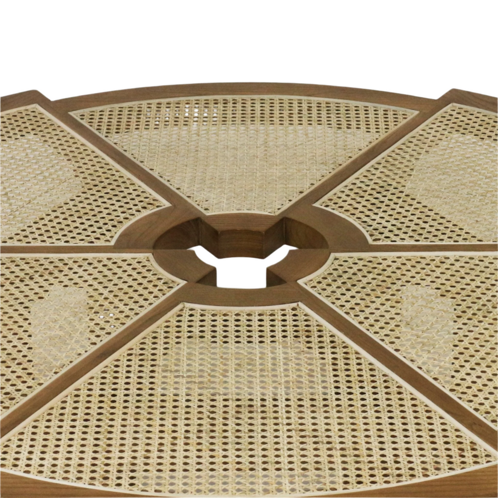 Close-up of a round coffee table top with natural cane weave panels set into a solid wood frame in a warm natural-blonde finish, showing radial segmented sections and a central circular cutout.
