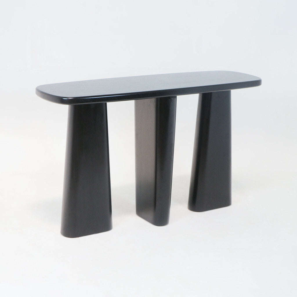 Black solid-wood console table with a rounded oval top and three sculptural tapered pedestal legs, modern minimalist silhouette ideal for an entryway or living room.