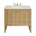 The NUEMA Sala 36 Single Bathroom Vanity features solid oak construction, vertical panels, two central cabinet doors, a lower drawer, a white stone countertop with inset sink, and gold faucet handles in a modern minimalist design.