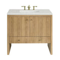Freestanding 36-inch single-sink bathroom vanity in light natural oak with vertical plank doors, white speckled stone countertop and rectangular undermount sink, fitted with polished brass widespread faucet and round brass knobs.