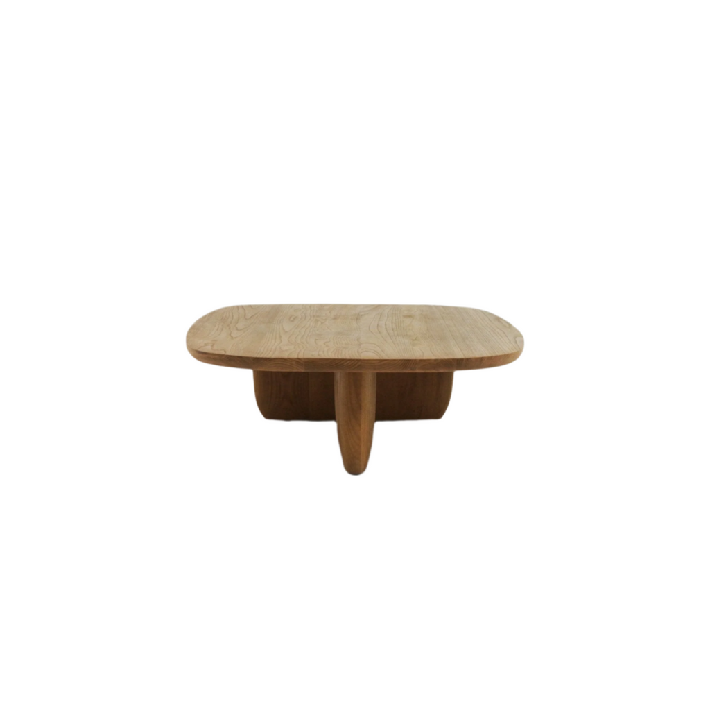 Low modern solid wood coffee table in a natural finish with a rounded rectangular top, visible wood grain and a sculpted central pedestal base that splits into three rounded supports.