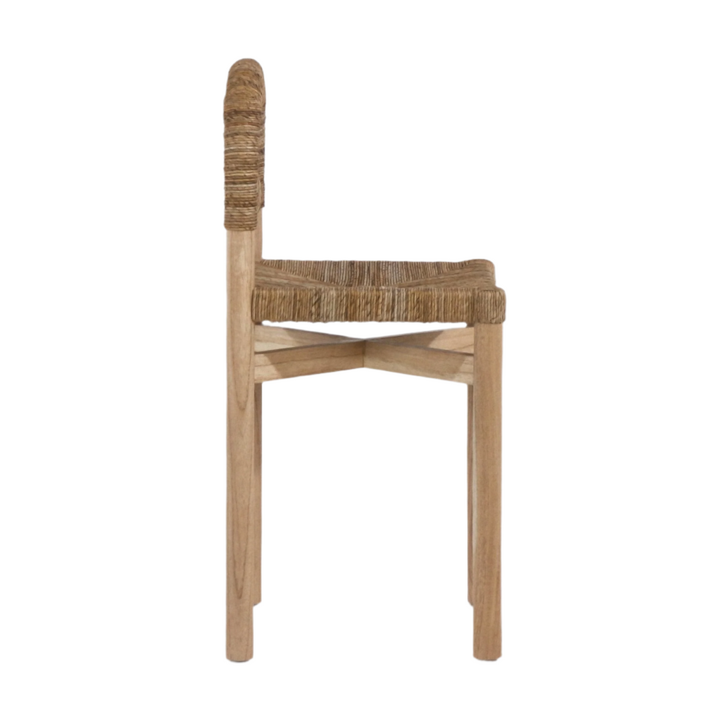 Side profile of a coastal counter-height stool with a natural oak frame, woven seagrass seat and rope-wrapped back, showing crossed stretcher support and tapered wooden legs.
