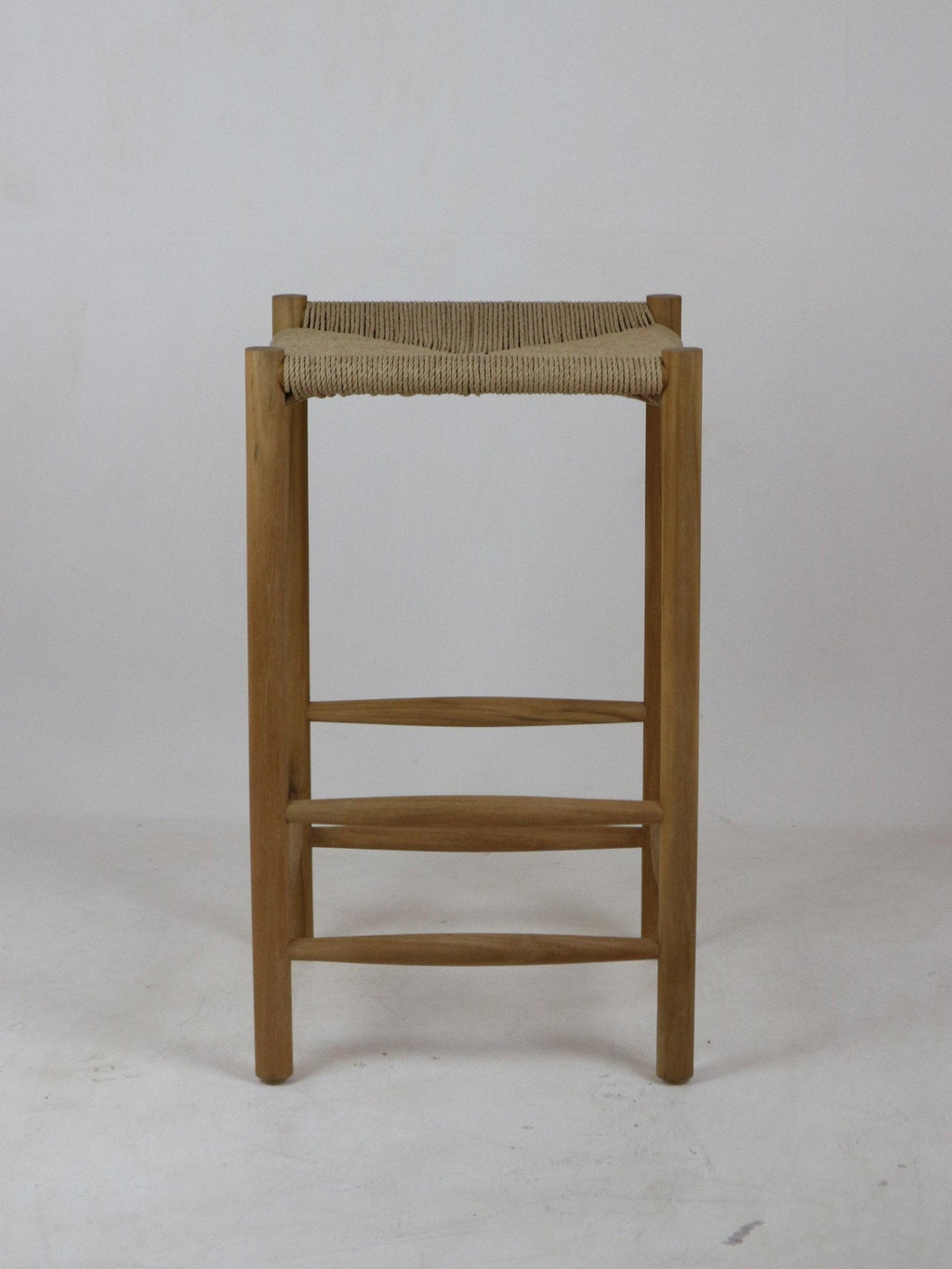 Front view of a natural solid wood bar stool with a woven beige rope seat, straight legs and horizontal wooden foot rails in a minimalist modern backless design.