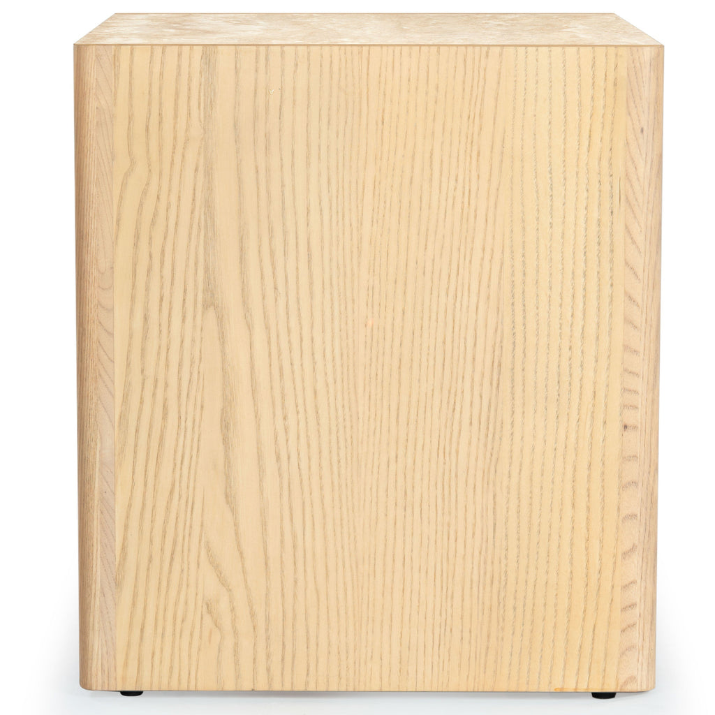 Side view of a natural ash wood nightstand showing vertical wood grain on the cabinet side, a thin light marble top edge and small black feet against a white background.