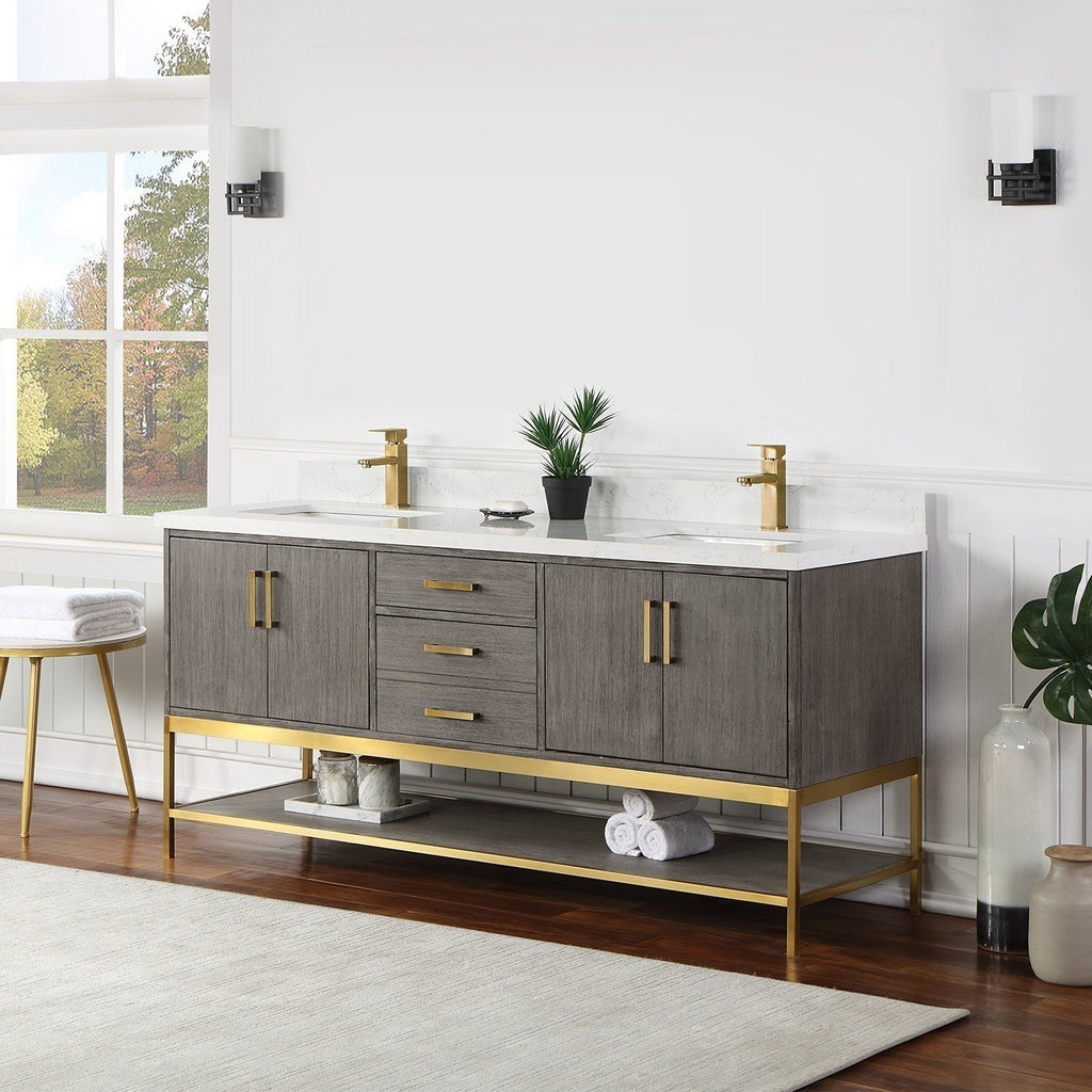Freestanding modern solid wood 72-inch double-sink bathroom vanity in stone finish with white stone countertop, gold faucets and hardware, central drawers and an open gold-accent lower shelf with rolled towels.