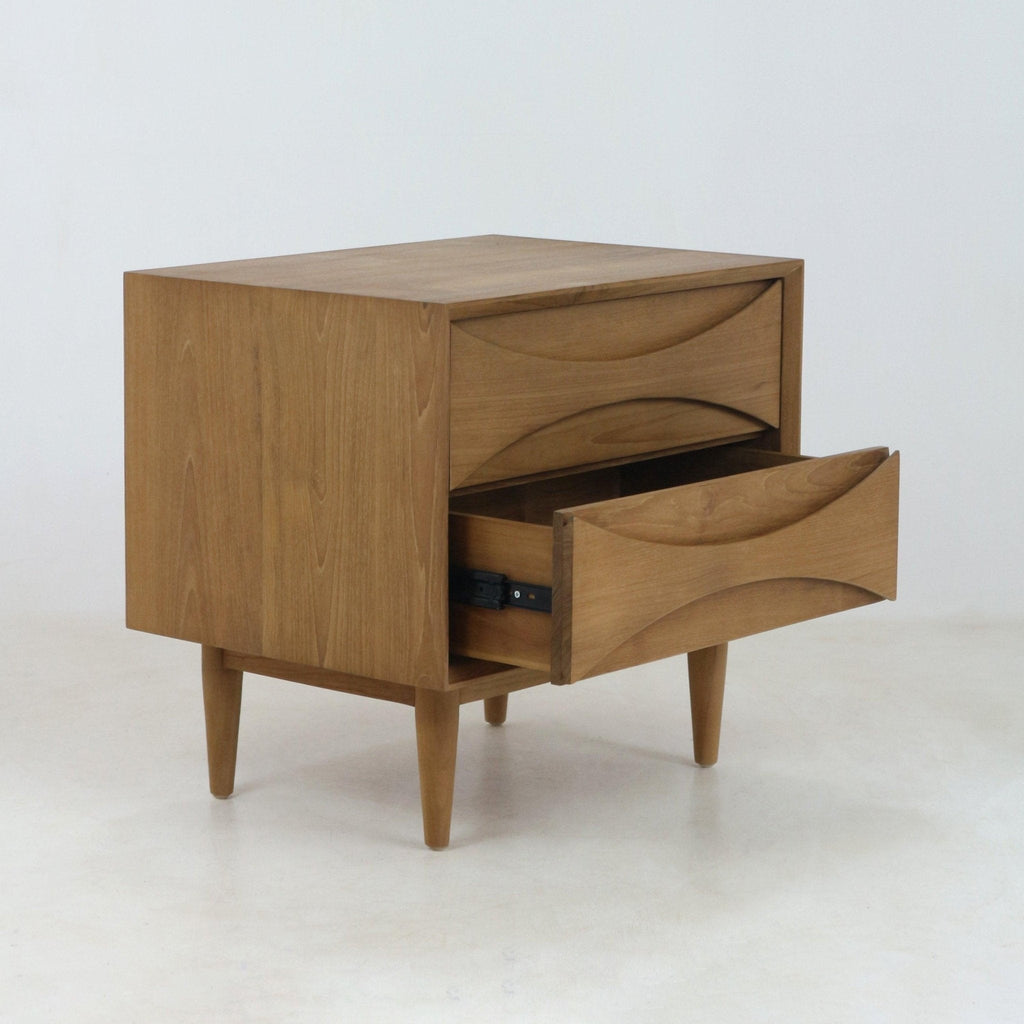 Solid teak nightstand in mid-century Scandinavian style with two drawers, carved recessed pull fronts and tapered legs, photographed on a white background with the lower drawer partially open.