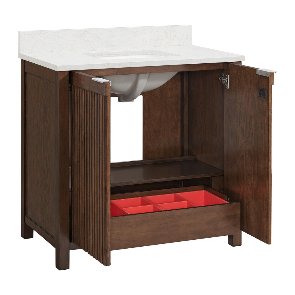 Modern solid-wood single-sink bathroom vanity with a white stone countertop and backsplash; brown fluted cabinet doors opened to reveal an interior shelf, a lower drawer with a red storage organizer, and the ceramic sink basin.
