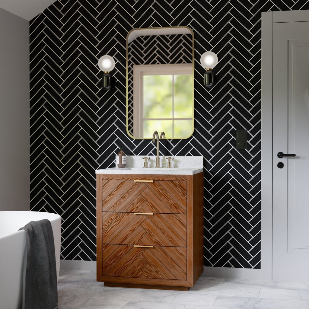 30-inch solid wood bathroom vanity with chevron wood drawer fronts and white stone countertop, single sink with brass faucet, shown against black herringbone tile, rounded mirror and twin globe wall sconces.