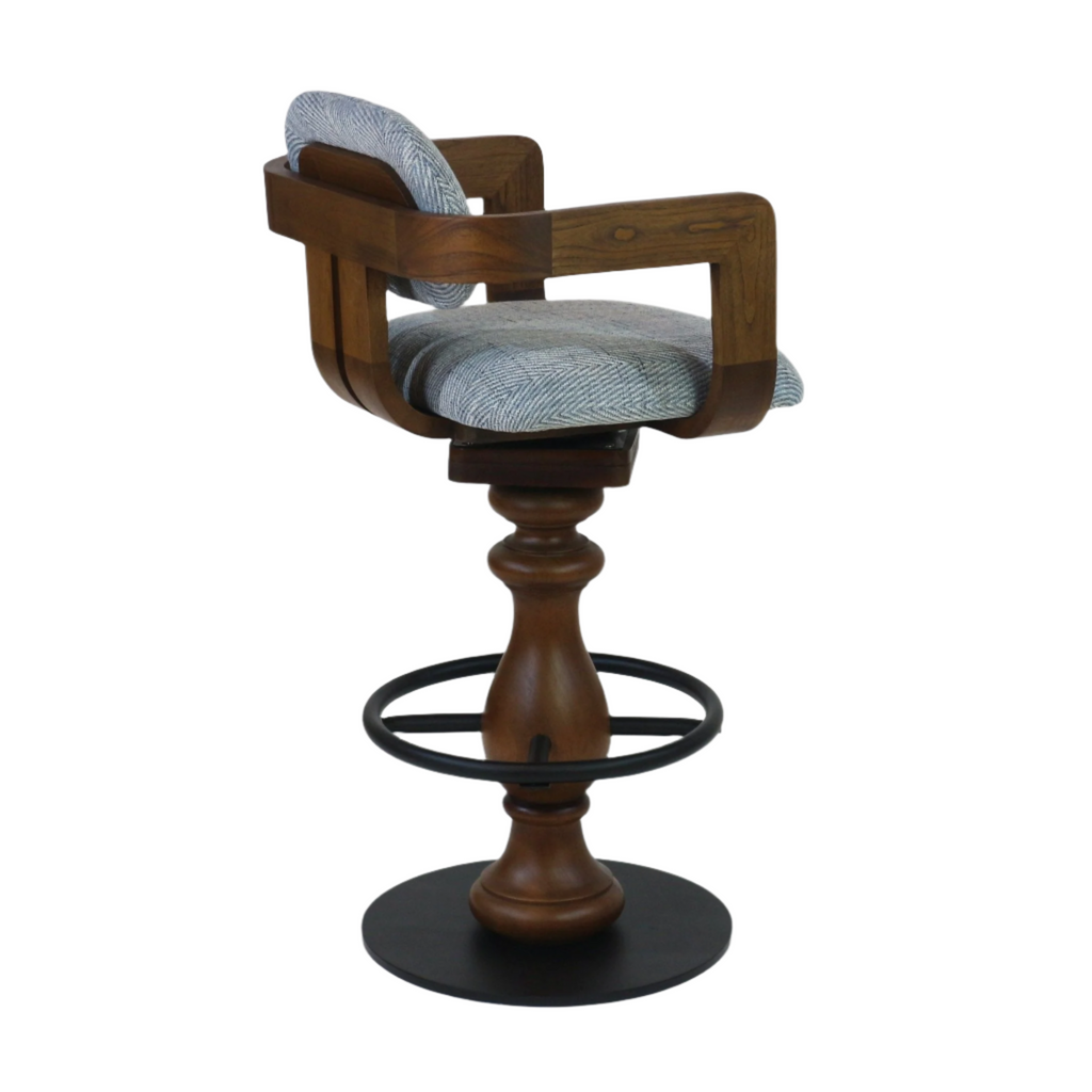 Swivel counter-height bar stool with light gray herringbone fabric seat and back, curved natural wood frame and turned wood pedestal, black metal circular footrest and round metal base.