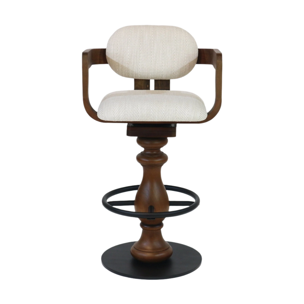 Beige upholstered bar stool with a rounded back and curved wooden armrests, turned natural wood pedestal, and black metal foot ring with a round base; counter-height swivel seat in a modern style.