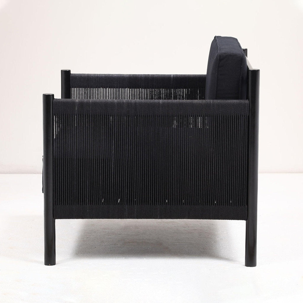 Side view of a modern black lounge chair featuring a solid wood frame, black papercord-wrapped arms and sides, and a cushioned black fabric seat and back.