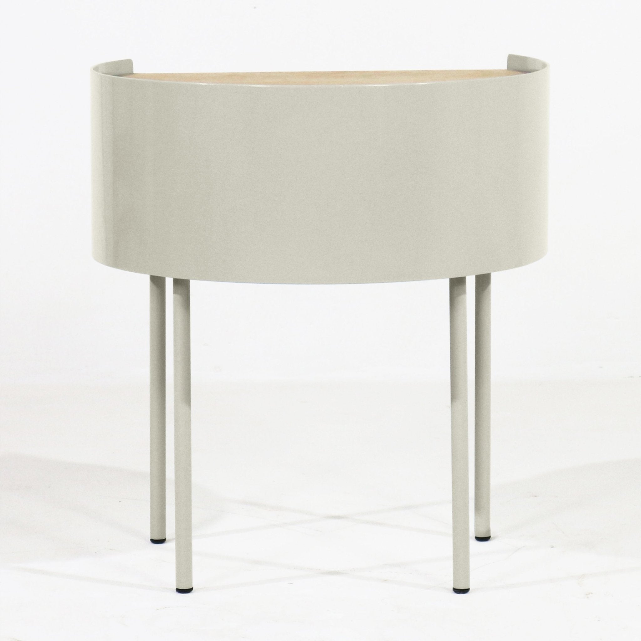 Modern curved nightstand with a light gray steel drum body, white oak top, and four slender steel legs, photographed on a white background.