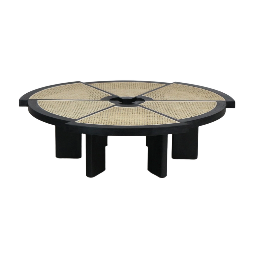 Low-profile round modern coffee table with a black solid-wood frame and six natural cane-woven wedge insets radiating from a central circular opening, supported by thick black block legs.