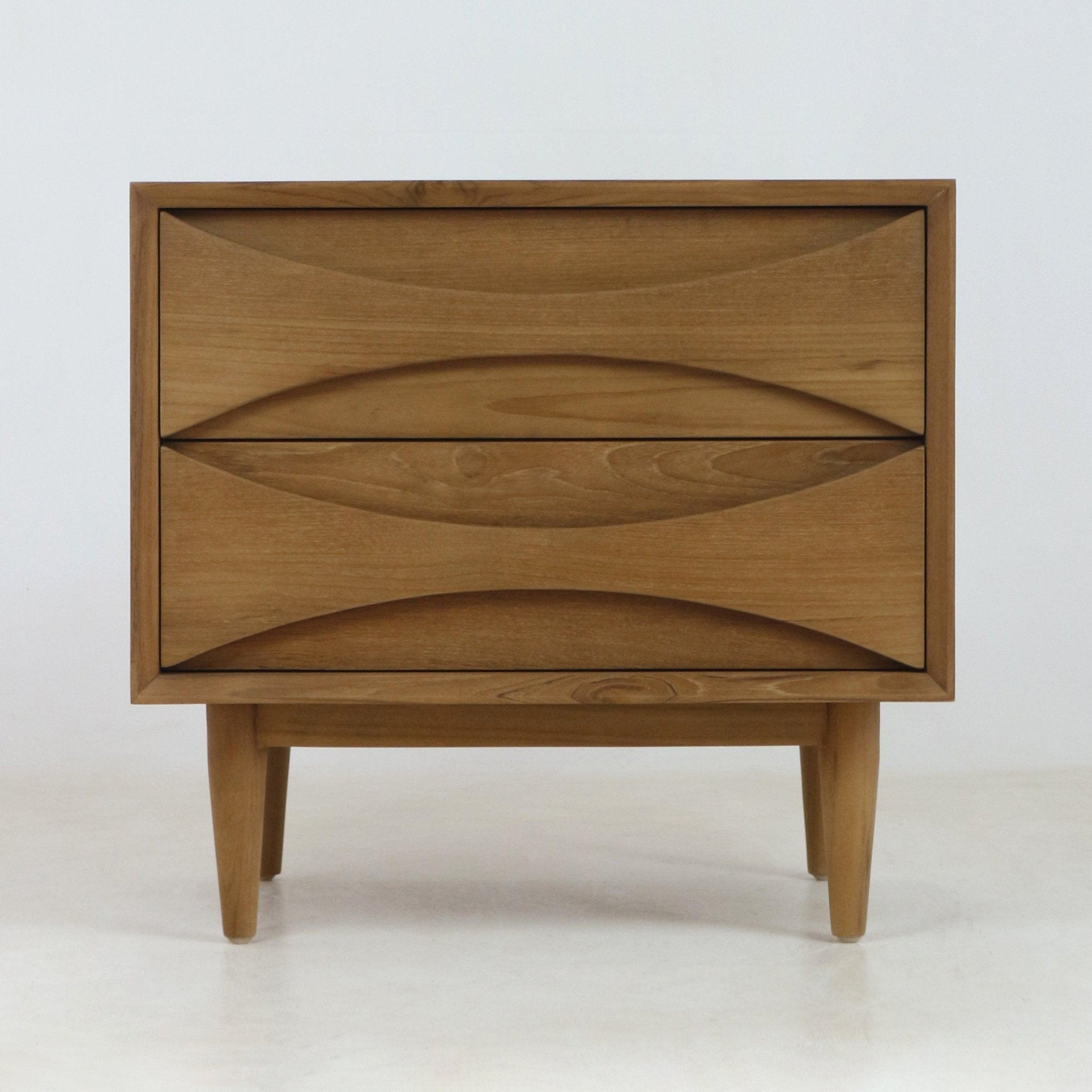 Natural teak solid wood nightstand with two drawers featuring carved recessed pulls, tapered mid-century modern legs and a clean Scandinavian silhouette.