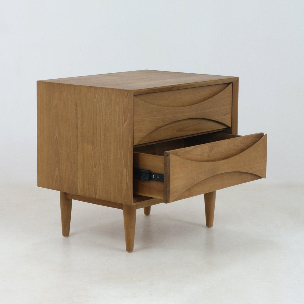 Solid teak nightstand in mid-century Scandinavian style with two drawers, carved recessed pull fronts and tapered legs, photographed on a white background with the lower drawer partially open.