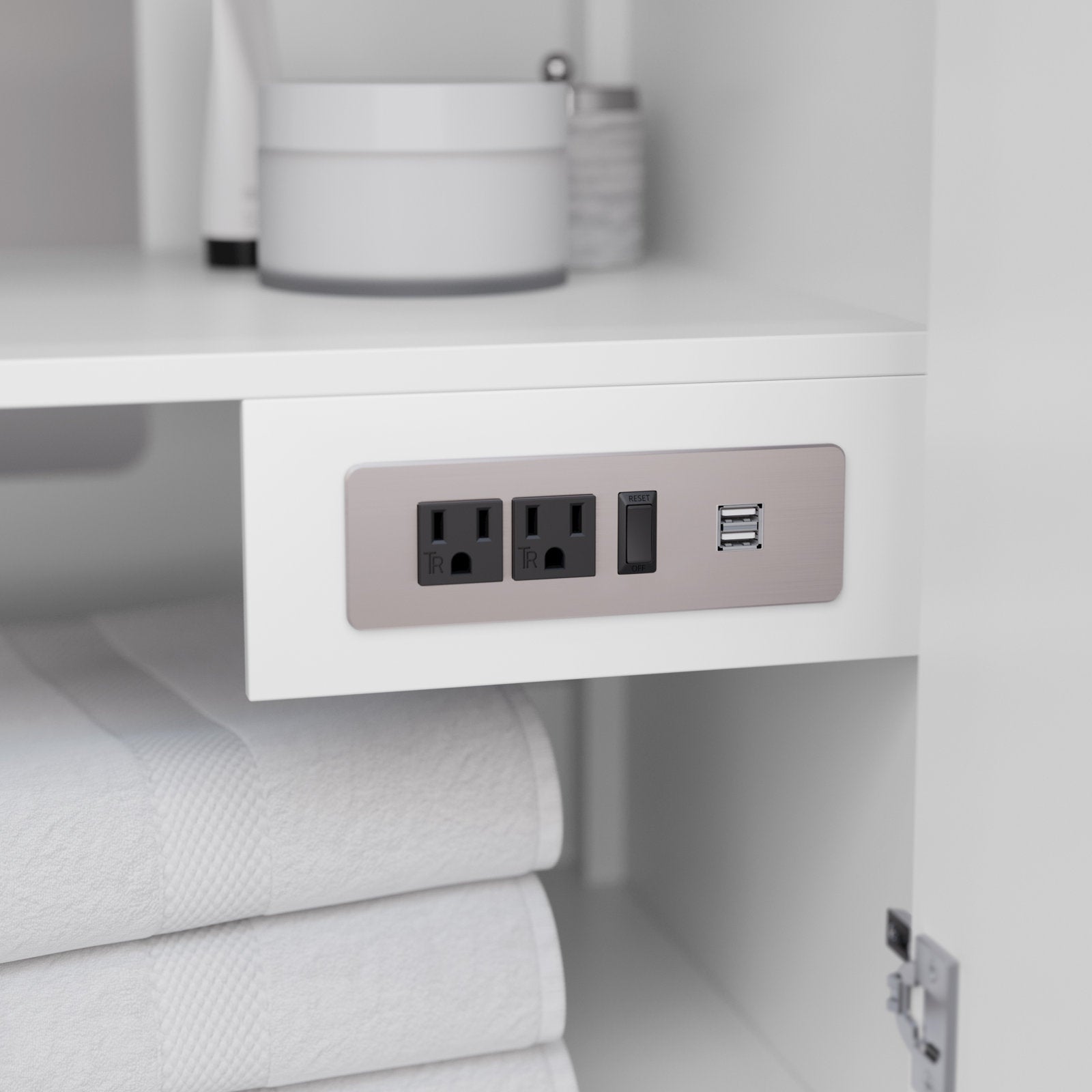 Close-up of a stone-colored bathroom vanity interior showing a brushed-metal outlet panel with two black power sockets, a reset switch and dual USB ports above neatly folded white towels.