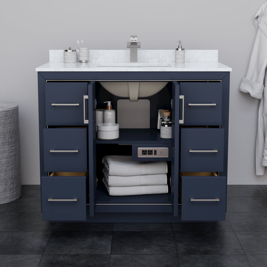 Modern 42-inch solid wood bathroom vanity in navy blue with a white stone countertop and undermount ceramic sink, brushed-nickel pulls, open center doors showing shelves with folded towels, toiletries and a built-in power outlet.
